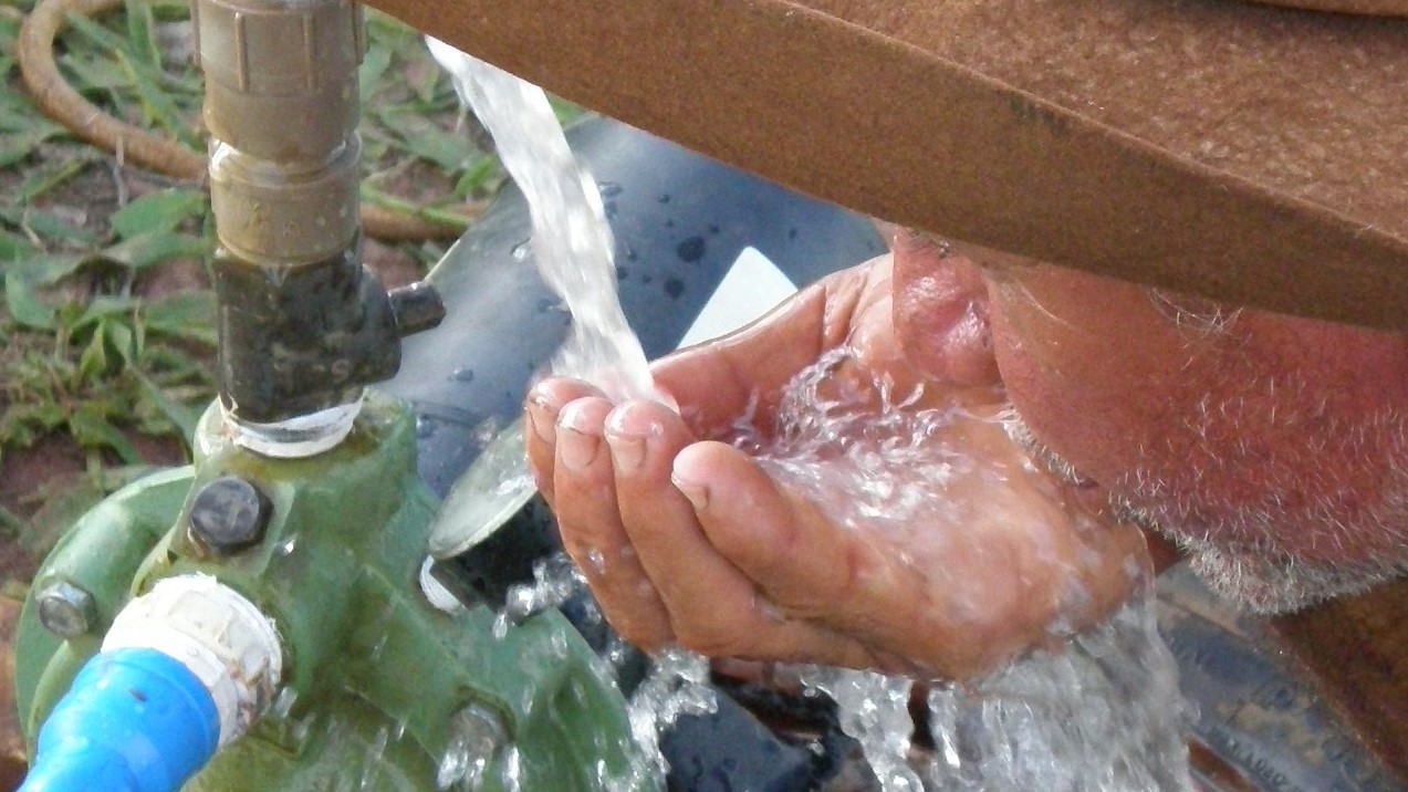 Ein Mann trinkt frisches klares Wasser direkt vom Brunnen.